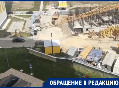 Башенный кран работает над  детской площадкой во дворе многоэтажки в Анапе