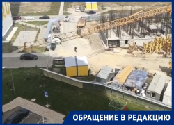 Башенный кран работает над  детской площадкой во дворе многоэтажки в Анапе